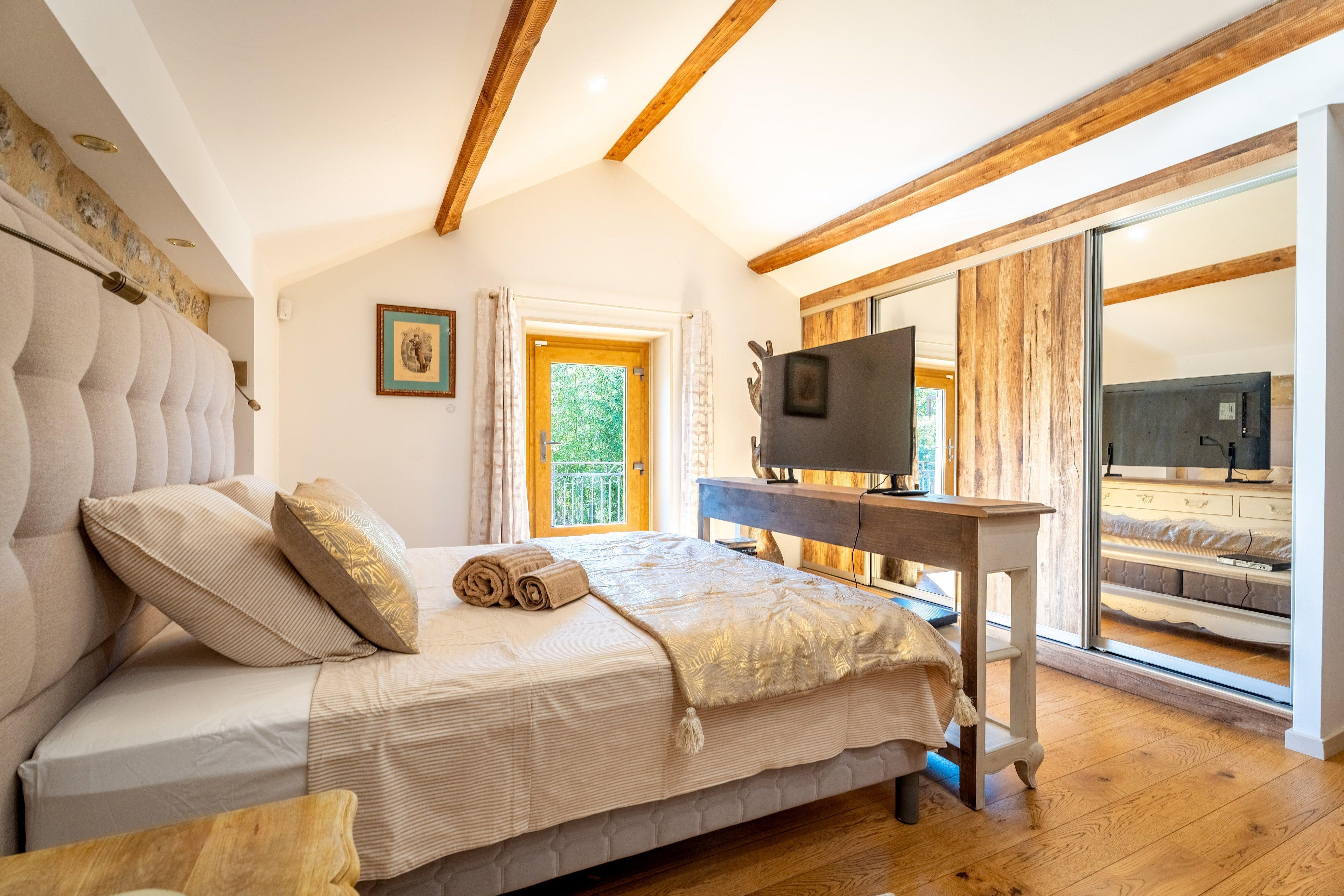 La chambre sous les combles, lit et poutres apparentes